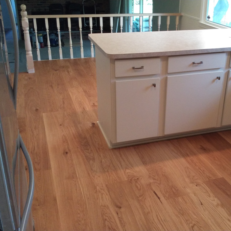 Wide plank 9/16" thick engineered prefinished flooring installed throughout kitchen, dining room, living room, foyer, and powder room.